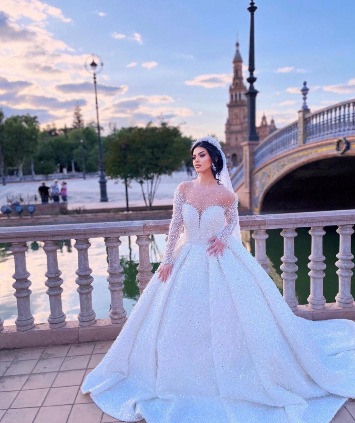 Novia con vestido de pedrería brillante en la Plaza de España de Sevilla al atardecer